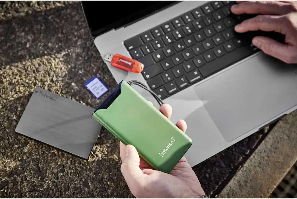 Intenso F20000 Green в руке рядом с ноутбуком